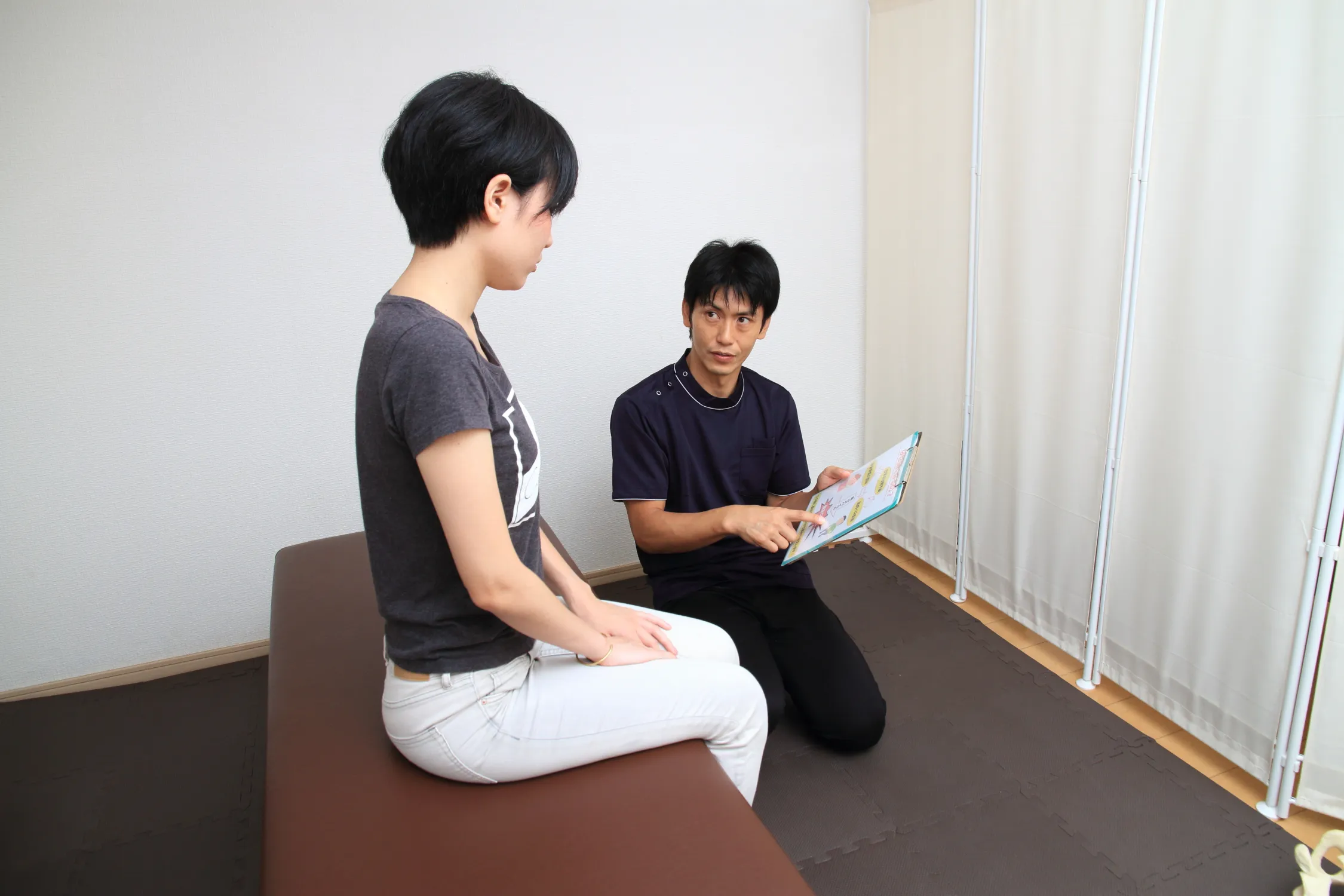 身体の状態などを女性に説明する男性スタッフの様子